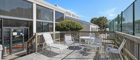 Terraza de madera con mobiliario exterior y zona de piscina cubierta con cristal.