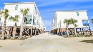 A beachfront property with two white buildings, each with a balcony and palm trees. - La Casita new Beach Cottage Easy Beach Access (Gulf Shores)