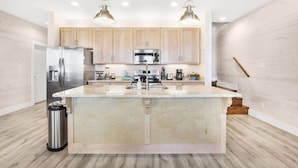 A modern kitchen with wooden cabinets, stainless steel appliances, and a large island. - La Casita new Beach Cottage Easy Beach Access (Gulf Shores)