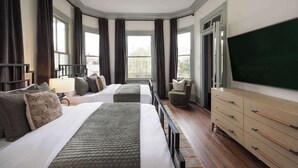 A hotel room with two beds, a large TV, a chair, and a dresser. - Historic Restoration, Whitefield Square (Savannah)