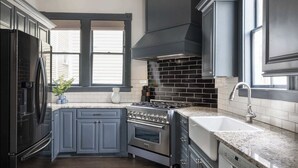 A modern kitchen with dark cabinetry, a stainless steel refrigerator, a gas range, and a built-in oven. - Historic Restoration, Whitefield Square (Savannah)
