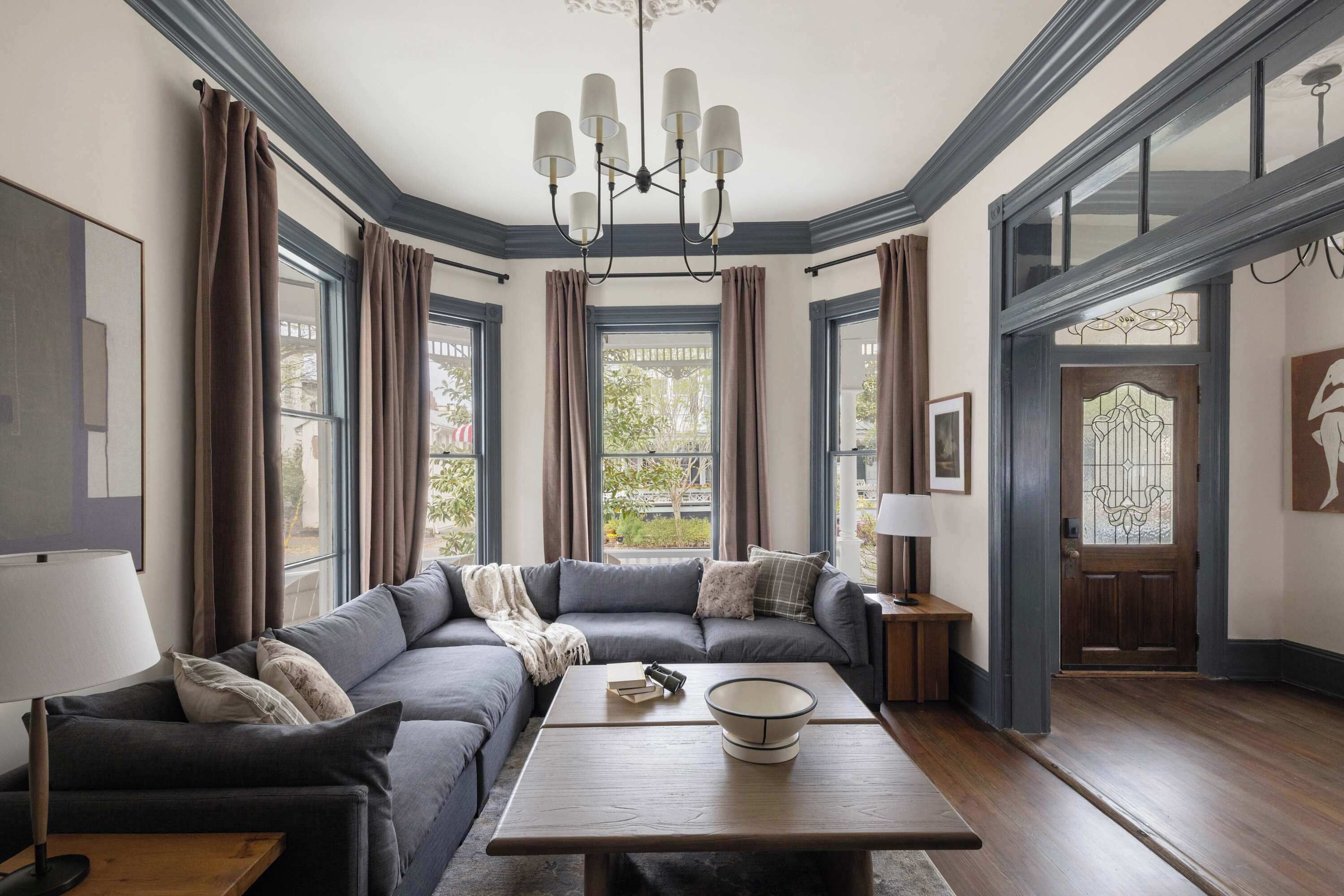 A modern living room with a sectional sofa, a wooden coffee table, and a chandelier.