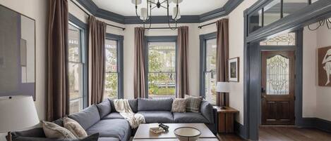A modern living room with a sectional sofa, a wooden coffee table, and a chandelier.
