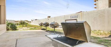 Una parrilla con rejilla de metal, un patio de concreto y un edificio con un letrero que dice "Horsehoes".