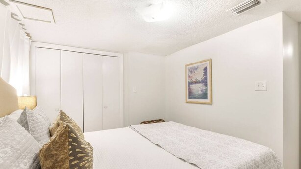 Ein Schlafzimmer mit Bett, Kissen, einem Kleiderschrank und einem Bild an der Wand.