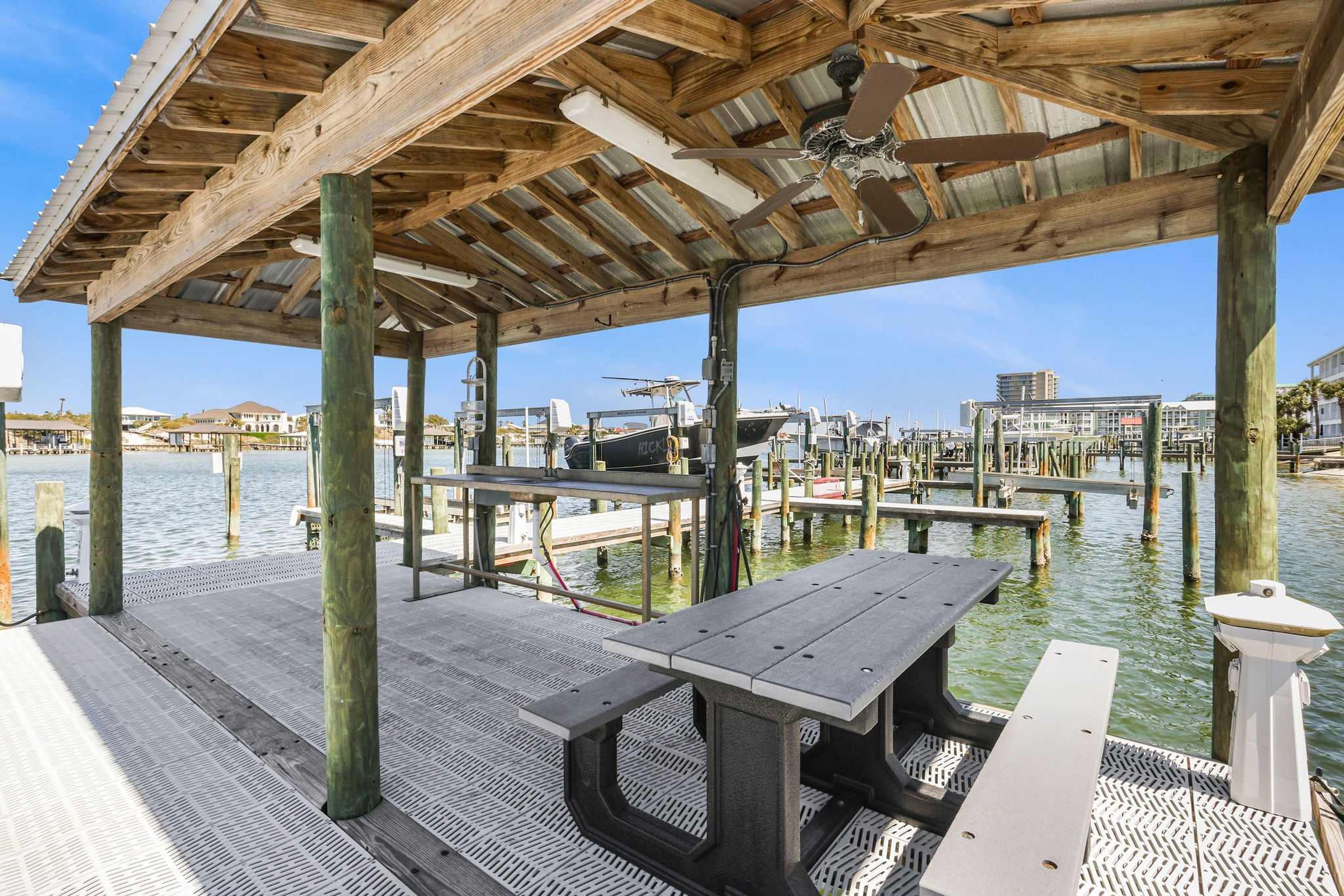 A wooden pier with a covered seating area, benches, and a small table.