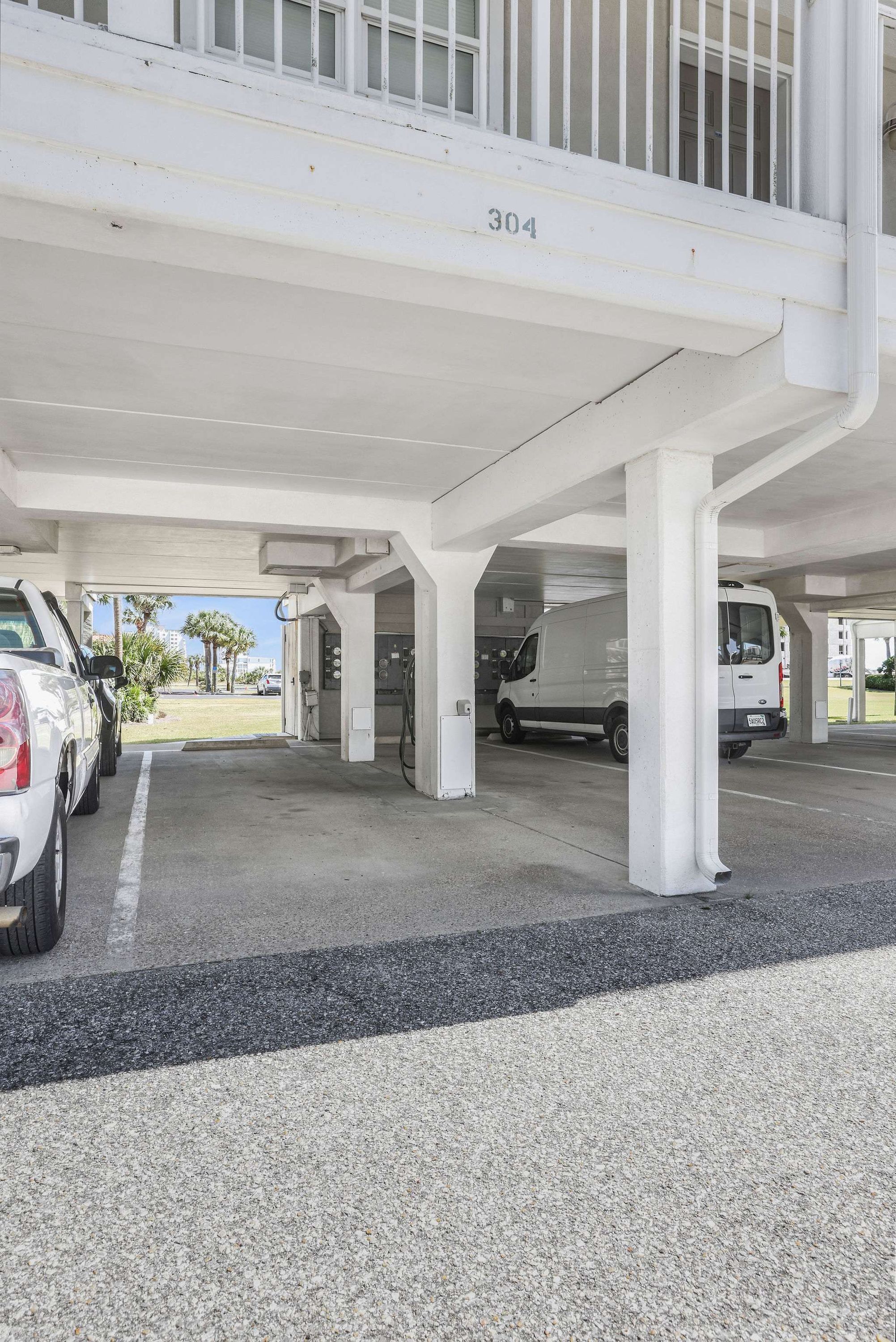 A parking garage with white pillars, a white van, and a white car parked.