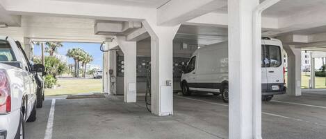 A parking garage with white pillars, a white van, and a white car parked.
