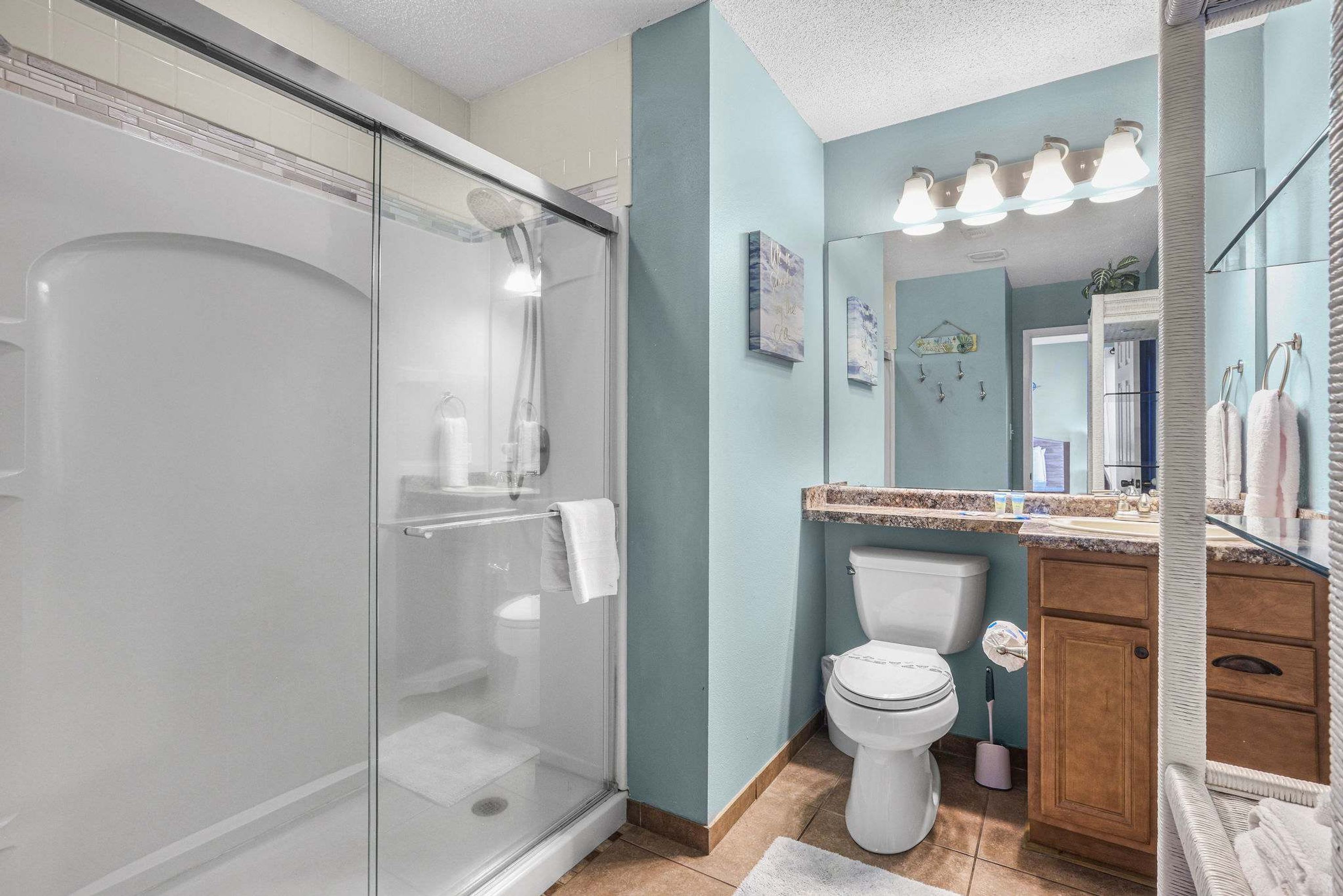 Un baño moderno con cabina de ducha acristalada, inodoro y tocador con espejo.