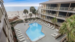 A pool area with lounge chairs and a view of the beach. - Sandpiper 1C- Stylish Gulf-side Affordable (Gulf Shores)