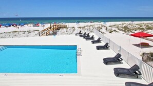 A poolside area with lounge chairs and a view of the beach. - Hammock Dunes Beachside Cottage (Orange Beach)