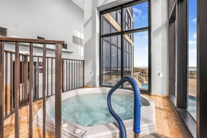 A hot tub with a blue hose, large windows, and a view of a building. - Phoenix II Orange Beach Beach Views Pools Fun (Orange Beach)