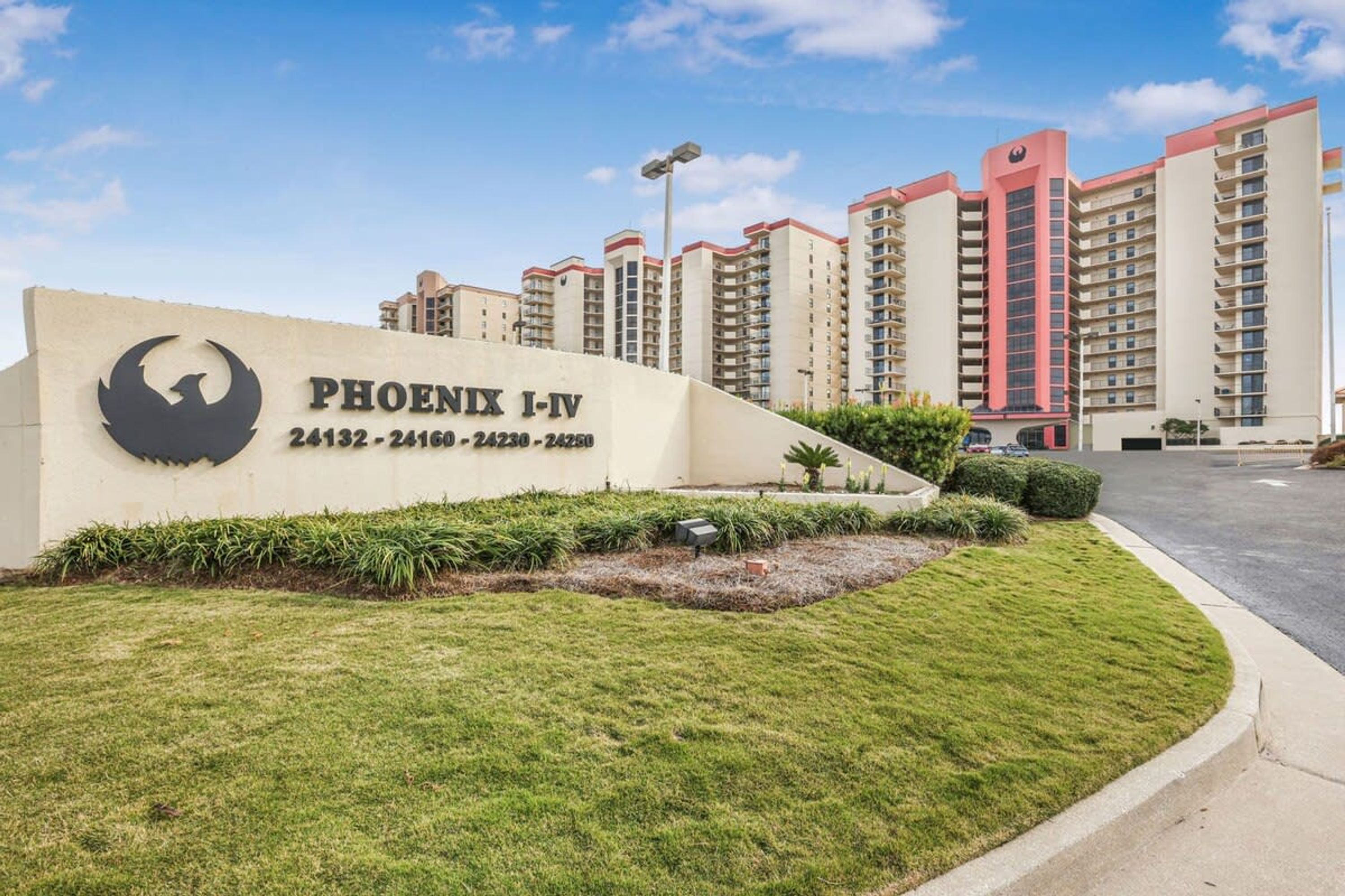 A sign for Phoenix I-IV with contact numbers, surrounded by well-maintained grass and a parking area.