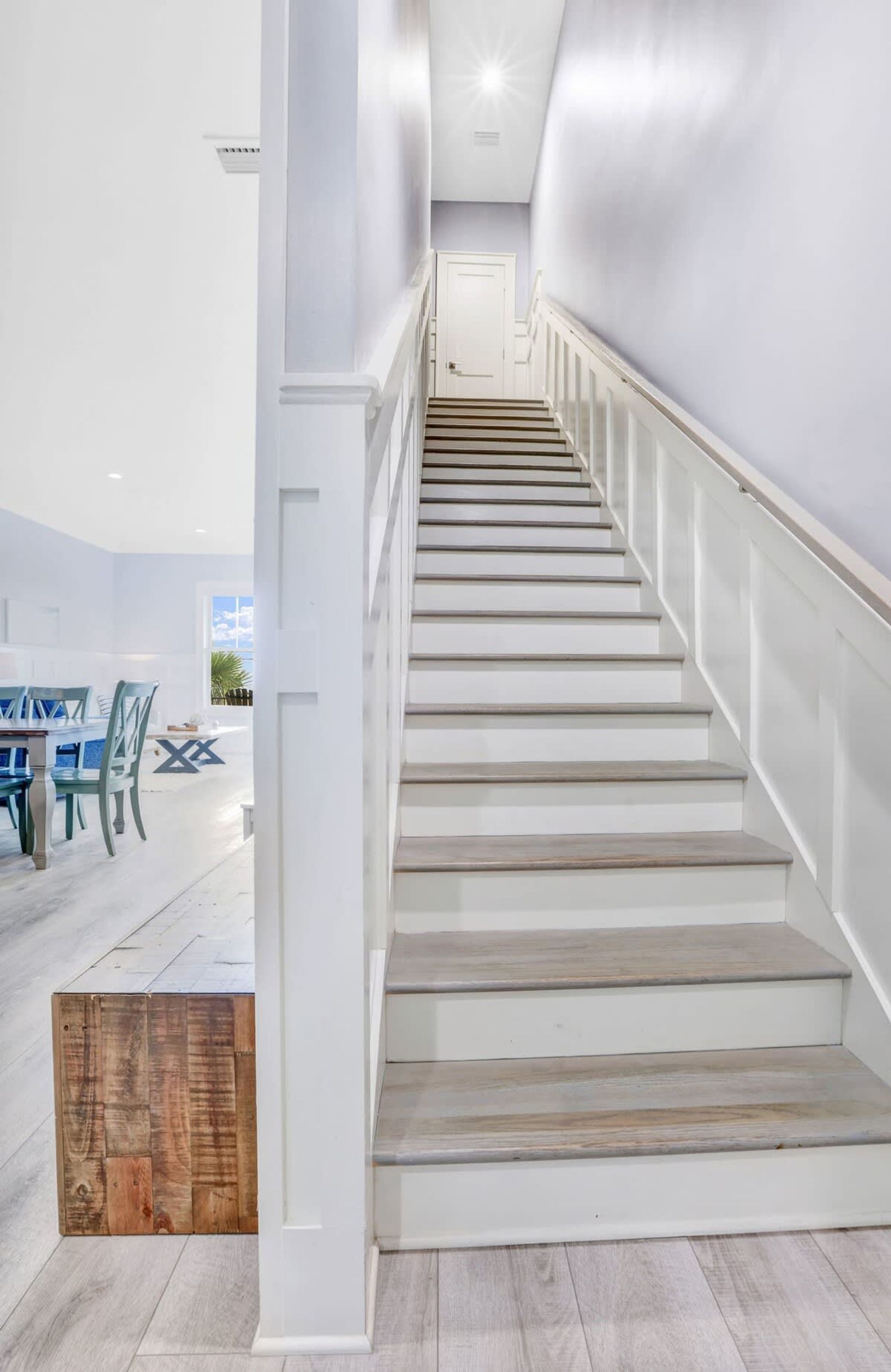 Una escalera con paredes blancas y escalones de madera que conduce a una puerta.