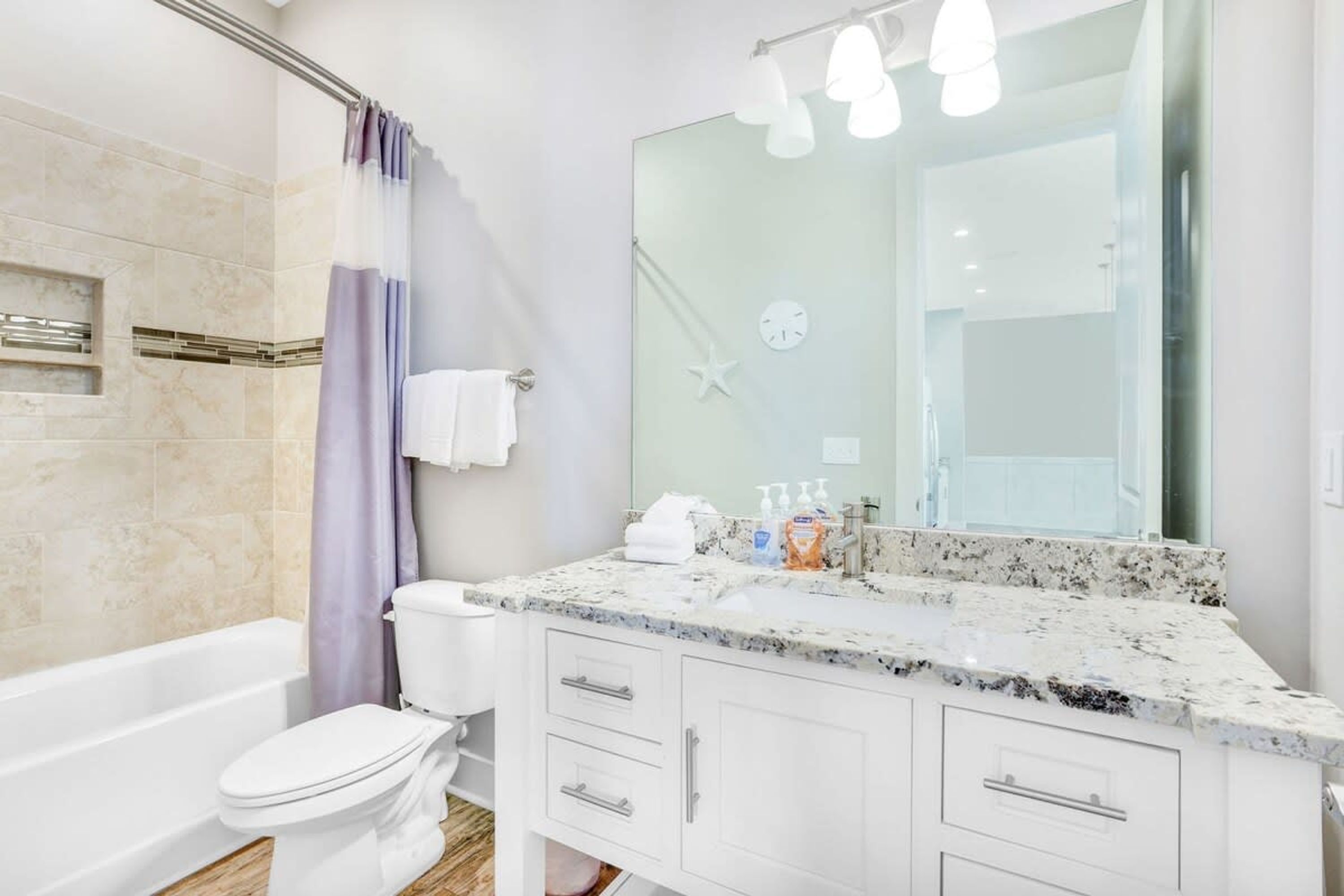 A modern bathroom with a white toilet, a shower with a glass door, and a marble sink vanity.