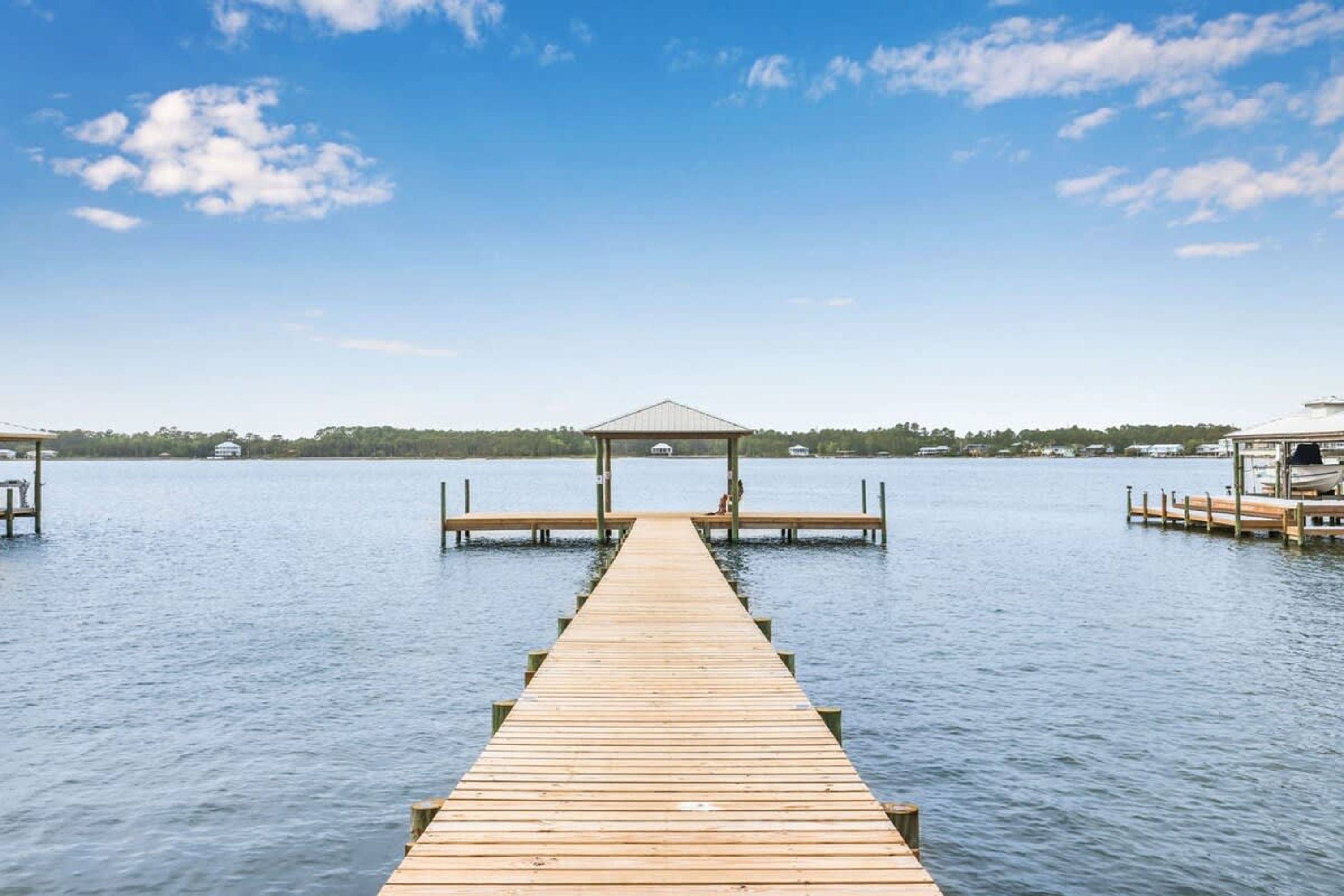 A wooden pier leading to a gazebo over water, with docks on either side.