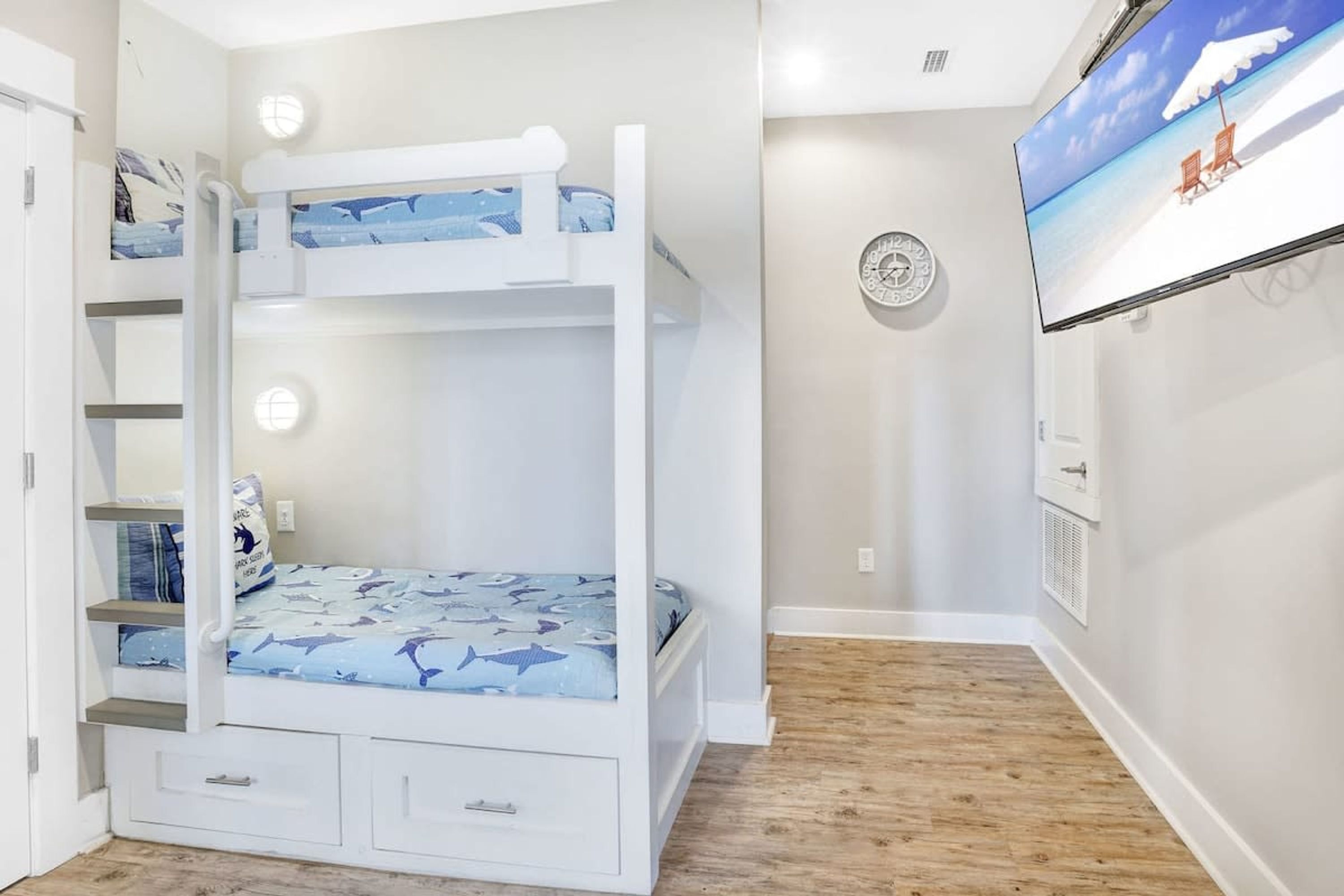 Un letto a castello con un letto inferiore, una piccola scrivania e una sveglia appesa al muro.