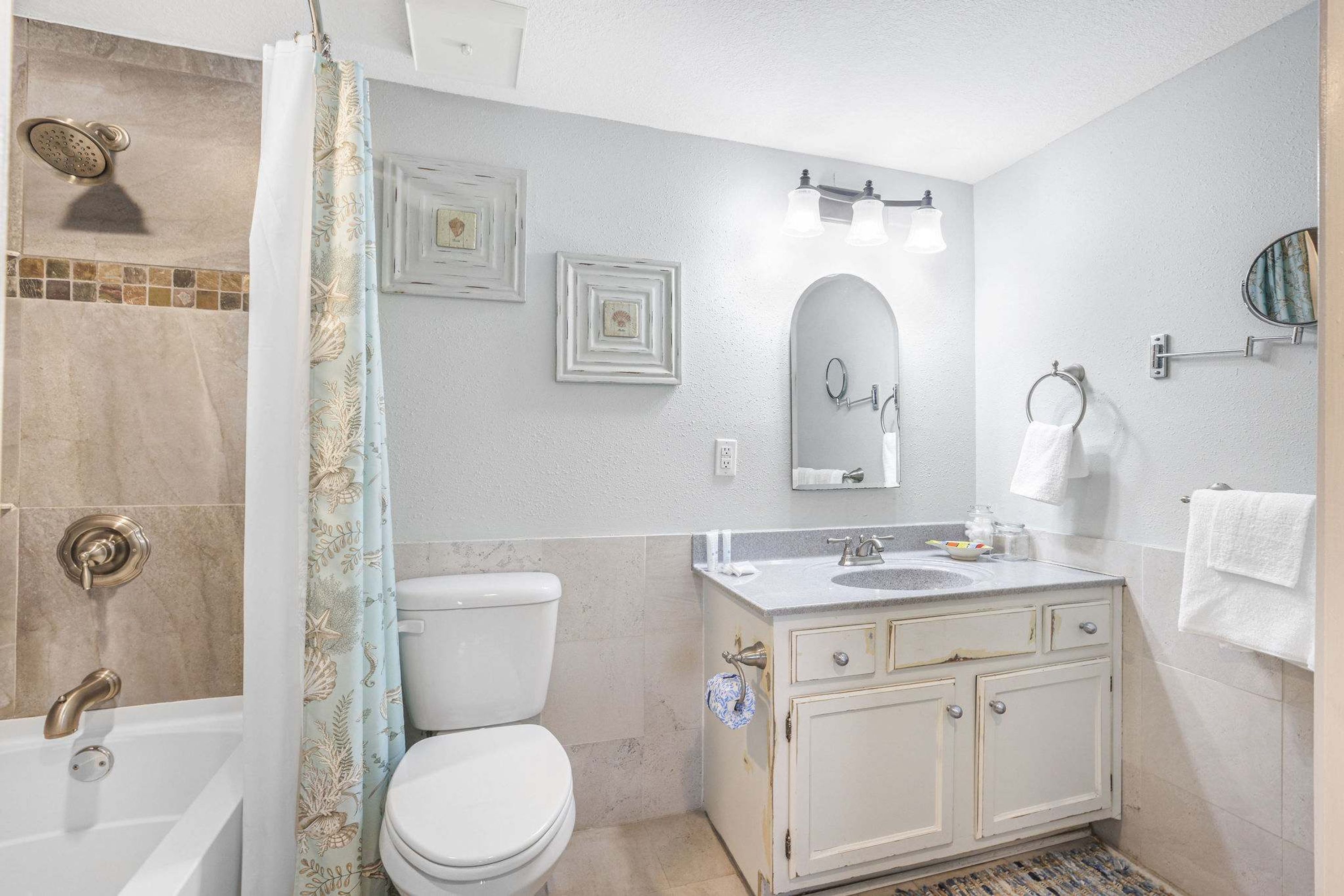 A bathroom with a bathtub, toilet, vanity, and shower.