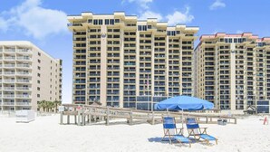 A beachfront hotel with multiple high-rise buildings, a sandy beach, and a wooden boardwalk with beach chairs and umbrellas. - Phoenix I 1112-11th Floor Splash pad Beachfront 2 Bedrooms 2 Baths (Orange Beach)