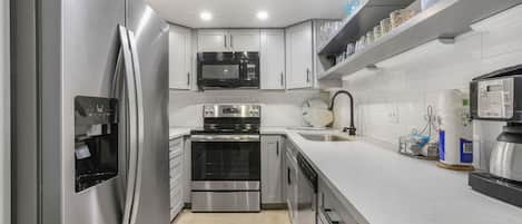 A modern kitchen with stainless steel appliances, white cabinetry, and a built-in microwave.