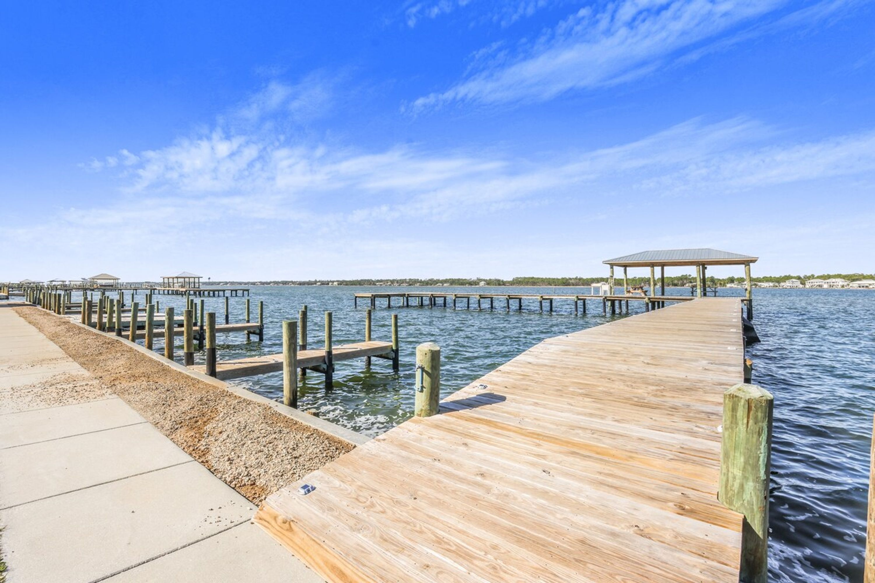A wooden pier extending into calm water with a clear sky.