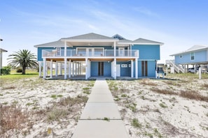 Ein zweistöckiges Strandhaus mit einer überdachten Veranda und einem Balkon.