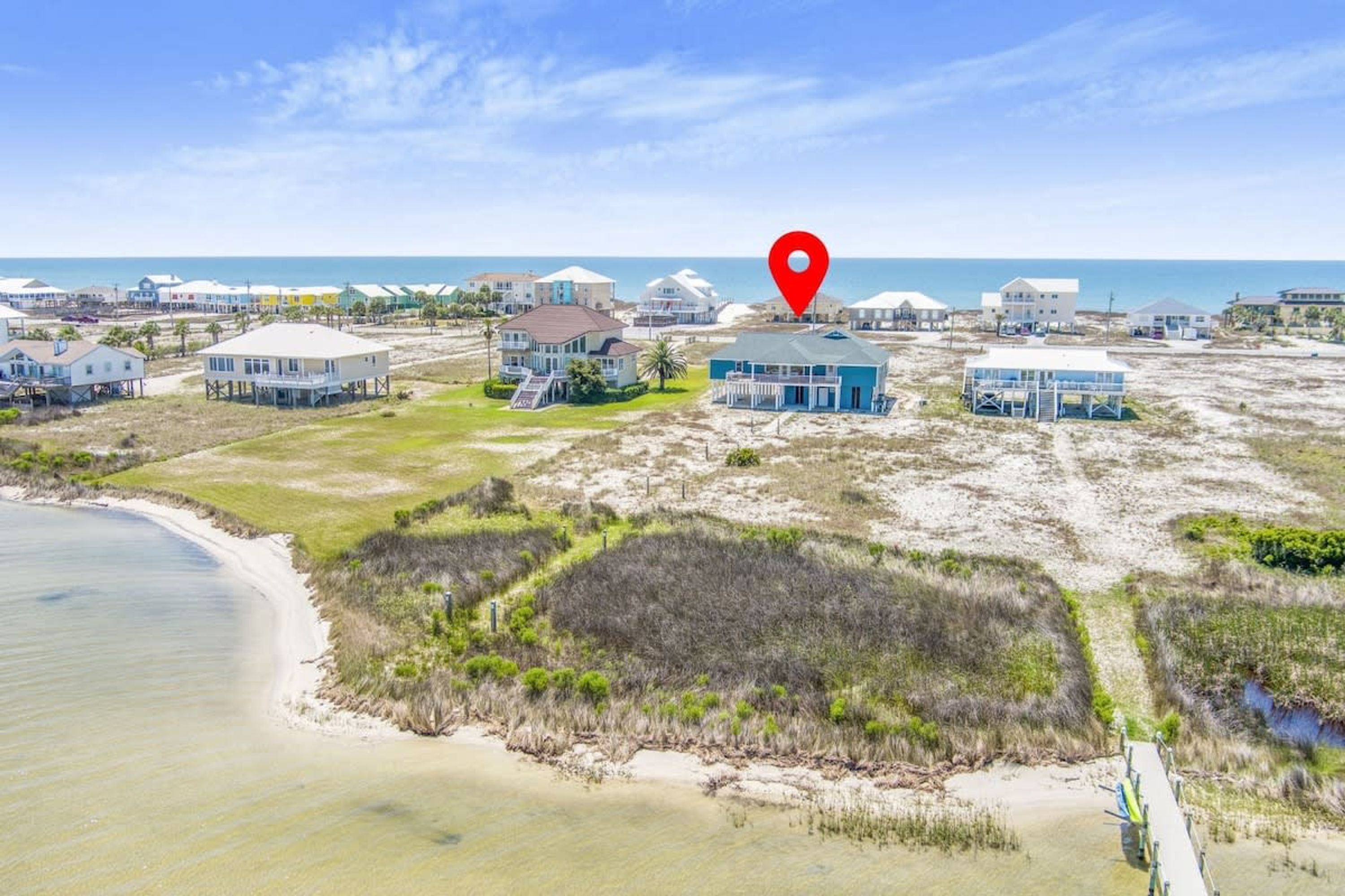 A coastal area with beachfront properties, including houses and a blue building with a porch.