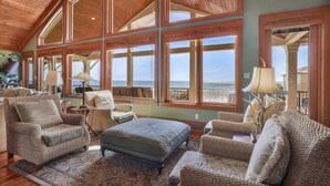 A spacious living room with large windows, wooden ceiling, and comfortable seating. - The Gayosa House 9BR Beachfront Oasis With Private Pool Hot Tub (Orange Beach)