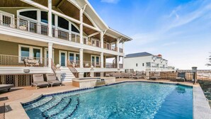 A two-story building with a swimming pool, outdoor seating, and a covered patio area. - The Gayosa House 9BR Beachfront Oasis With Private Pool Hot Tub (Orange Beach)