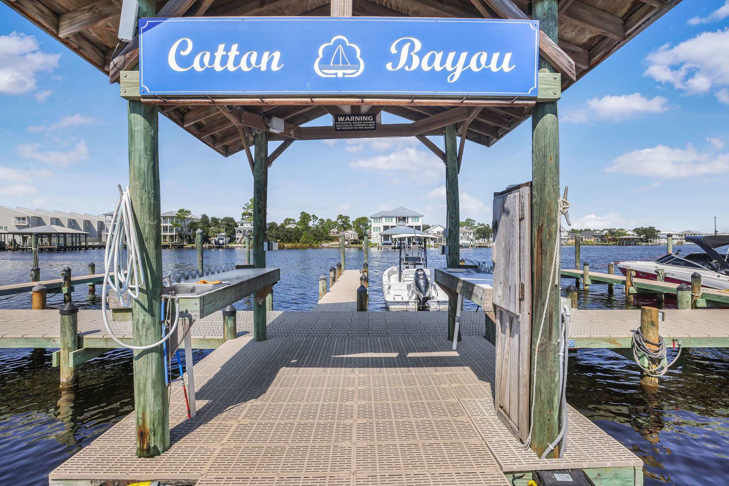 Een steiger met een bord waarop 'Cottage Bayou' staat en een waarschuwingsbord eronder.