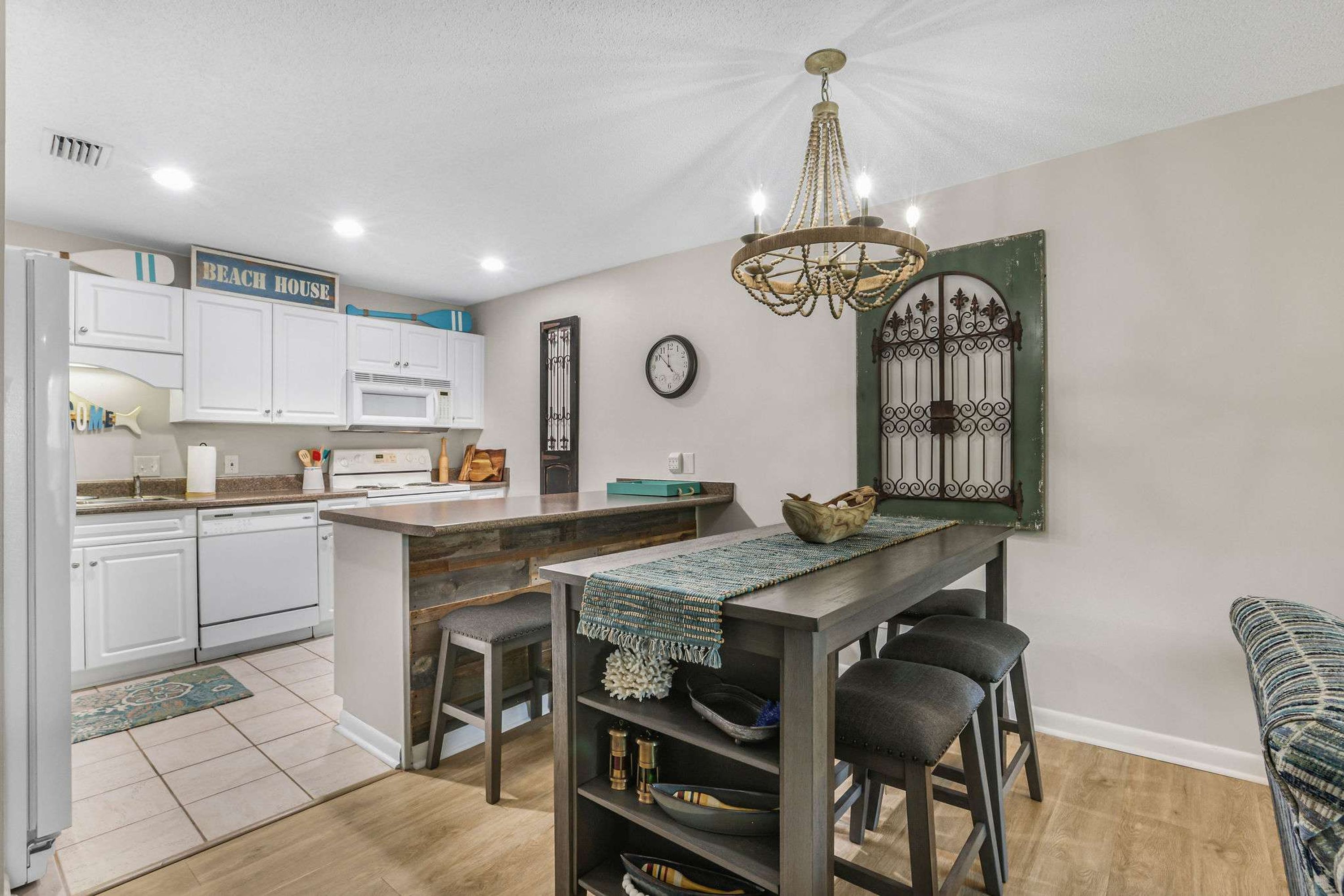 A modern kitchen with white cabinets, a central island, and a chandelier.