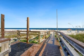 Un muelle de madera que lleva a una playa con cielos despejados.