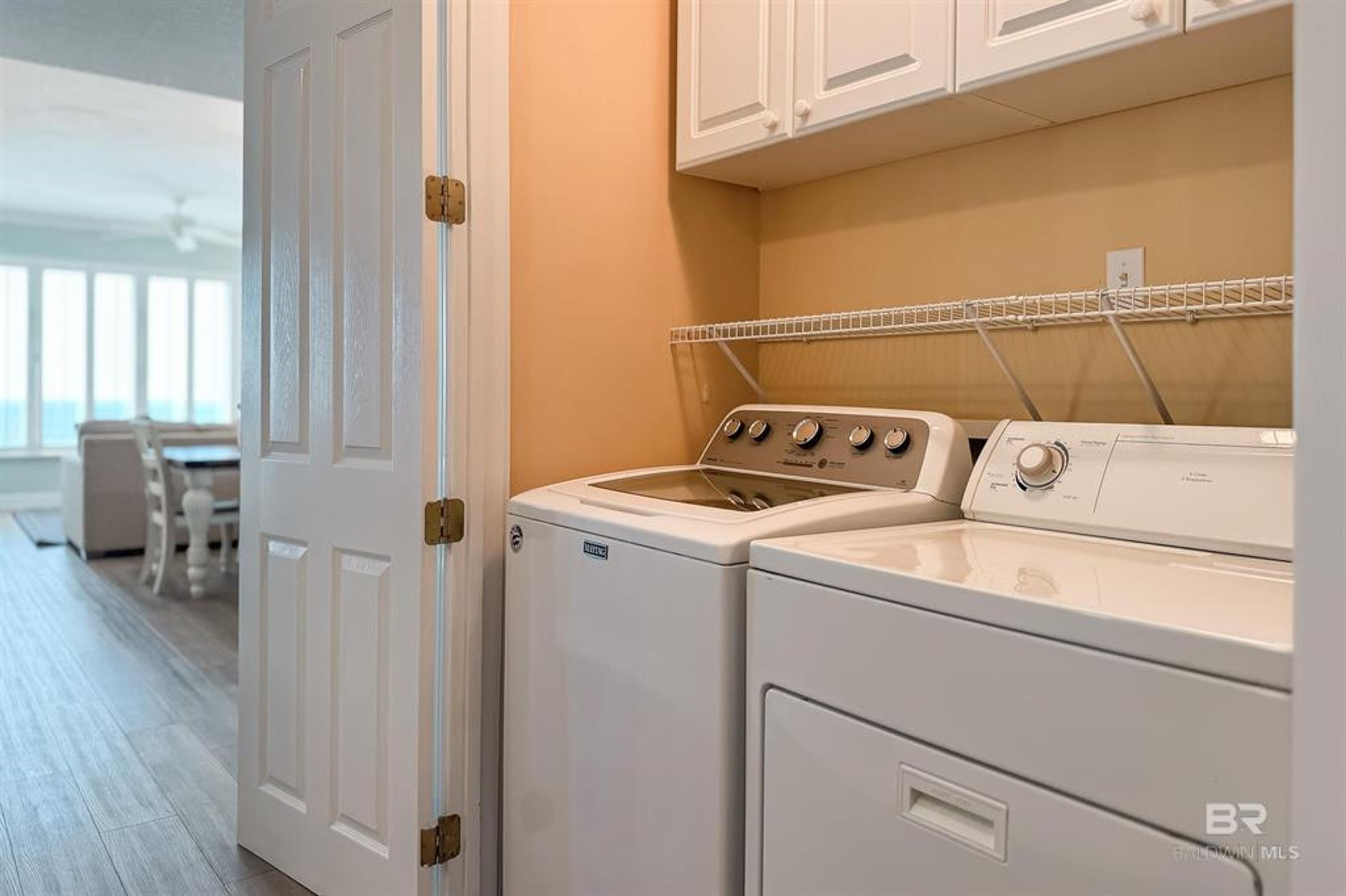 A laundry area with a washing machine and dryer, a white door, and a window with a view of the outside.