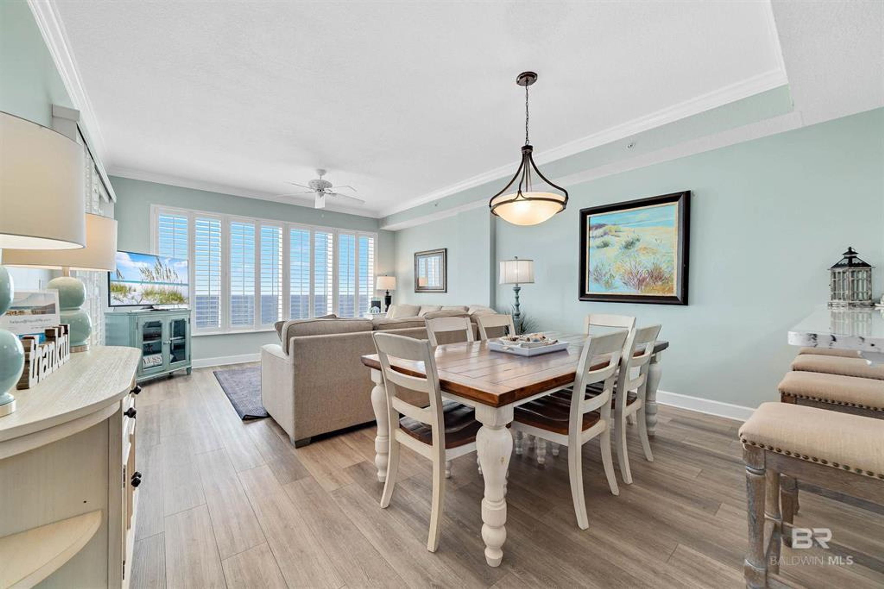 A spacious living area with a dining table and chairs, a sofa, and a ceiling fan.