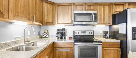 A kitchen with wooden cabinets, stainless steel appliances, a dishwasher, and granite countertops.