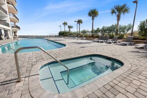 Ein Poolbereich mit zwei Pools, Liegestühlen und Palmen.