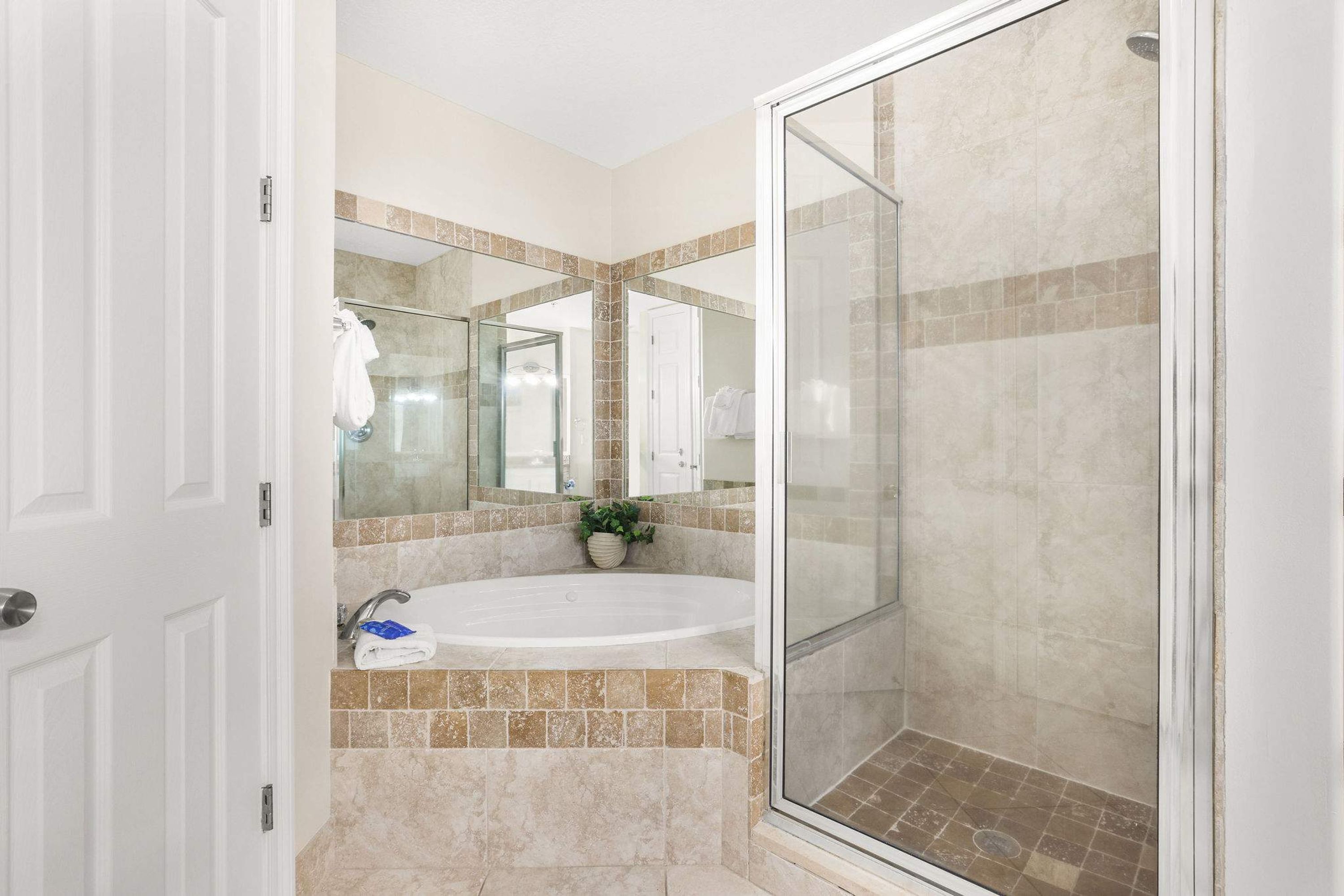 A bathroom with a bathtub, a glass shower enclosure, and a tiled floor.