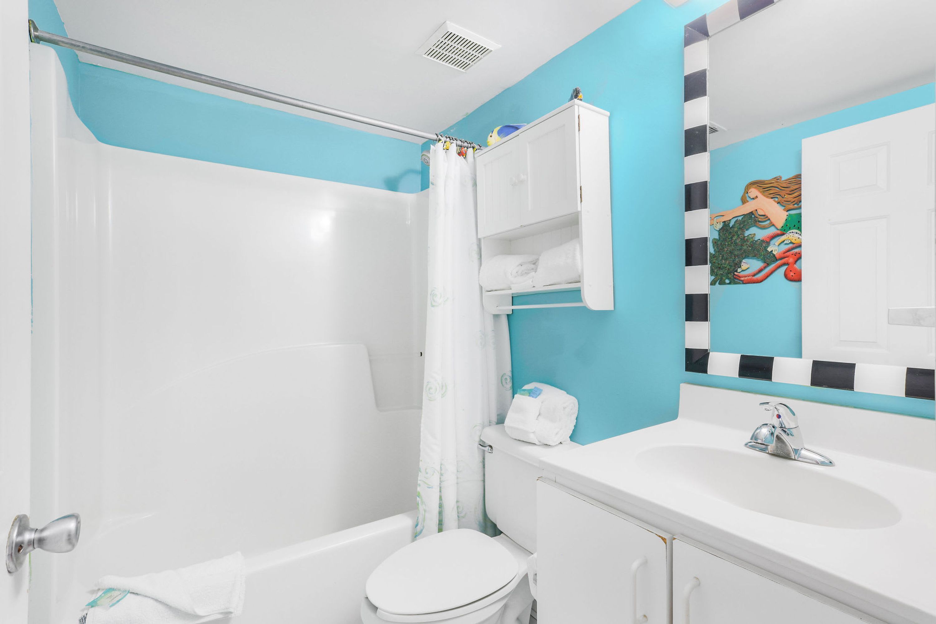 A bathroom with a bathtub, toilet, sink, and a shower curtain.