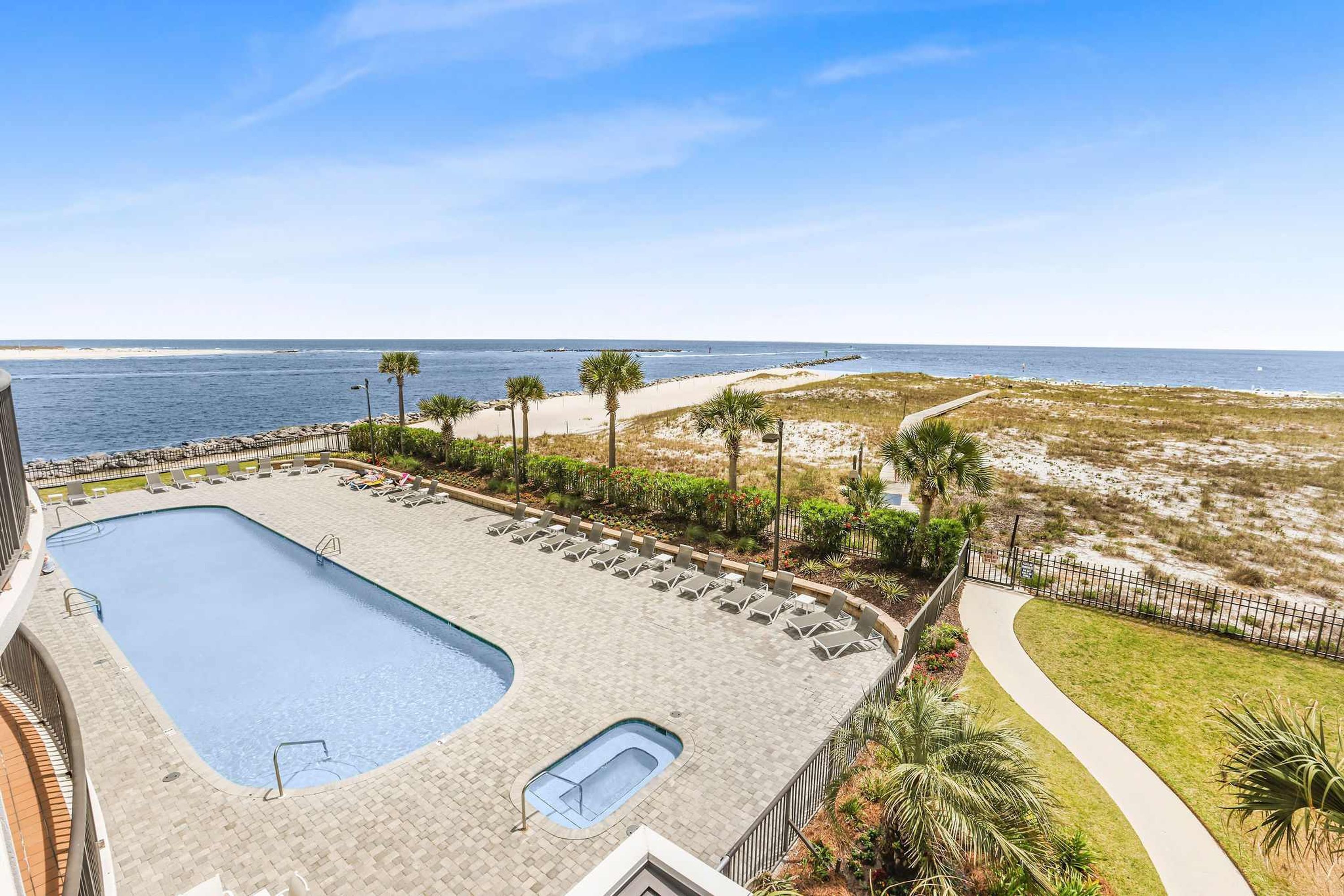 A rooftop pool with a view of the ocean, surrounded by palm trees and a sandy beach.