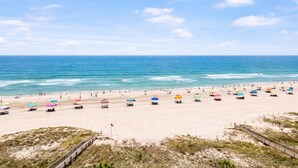 Una spiaggia con un'ampia zona sabbiosa, una recinzione in legno e una bandiera.