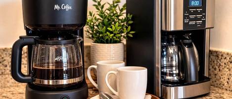 A coffee maker and a digital clock on a countertop.