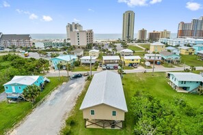 A coastal residential area with a mix of single-story houses and multi-story buildings, a clear view of the beach, and a road leading to the beach. - Don t Worry Beach House 3 2 2 Blocks to Beach (Gulf Shores)
