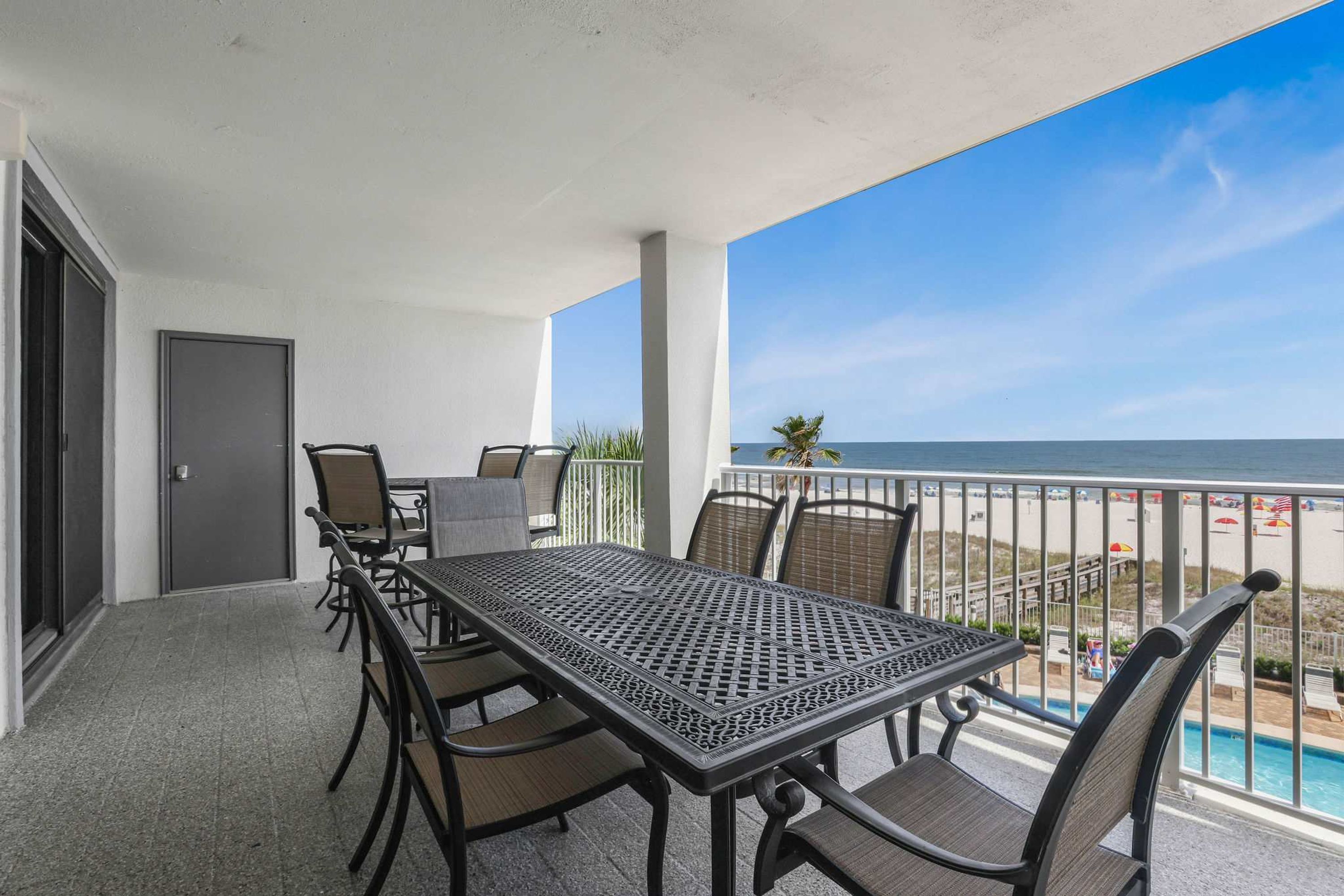 Ein Balkon mit Tisch und Stühlen mit Blick auf Strand und Poolbereich.