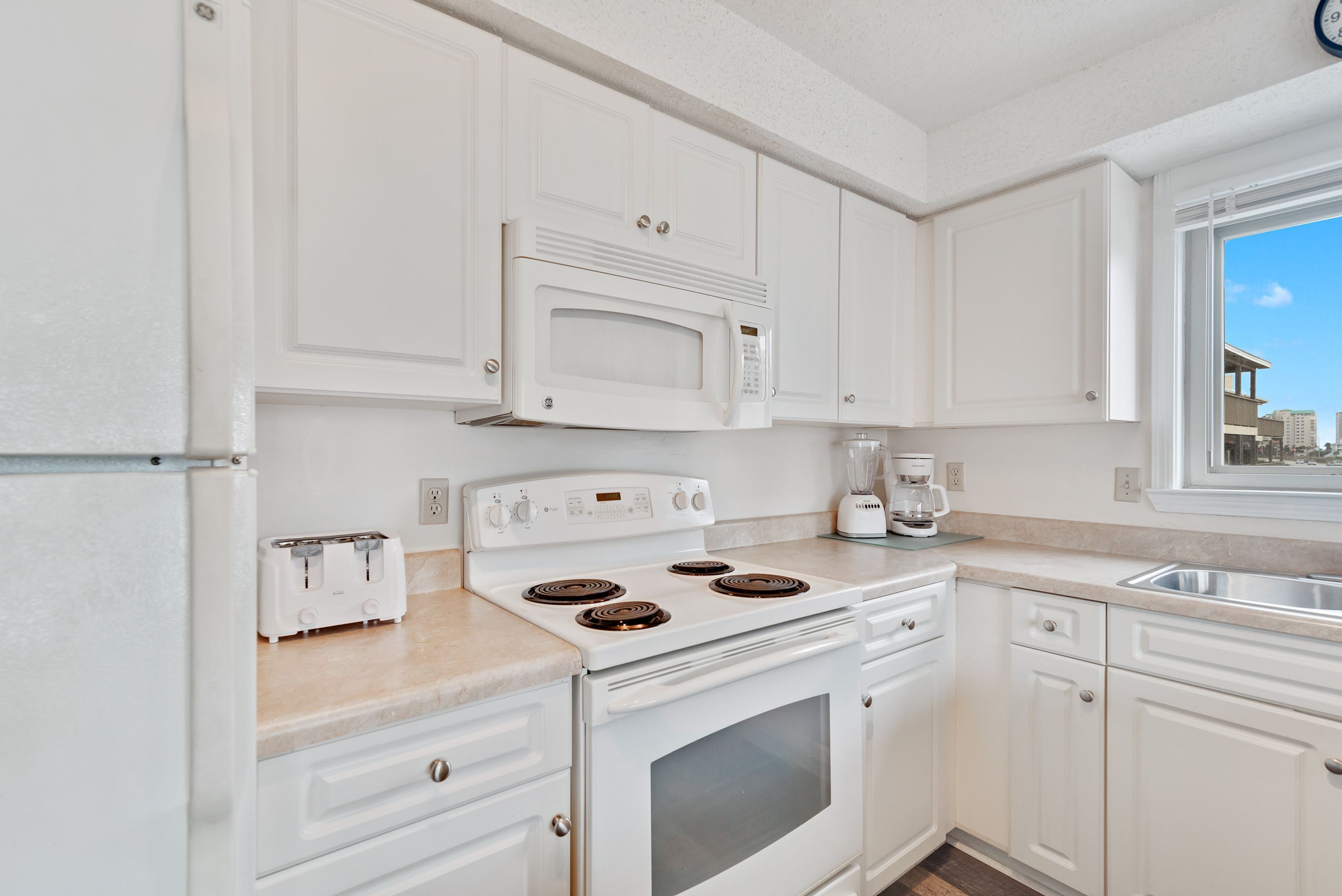 A kitchen with white cabinets, a built-in microwave, a stove, and a toaster.