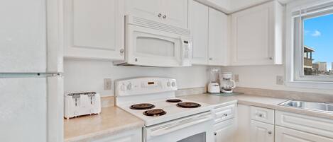 A kitchen with white cabinets, a built-in microwave, a stove, and a toaster.