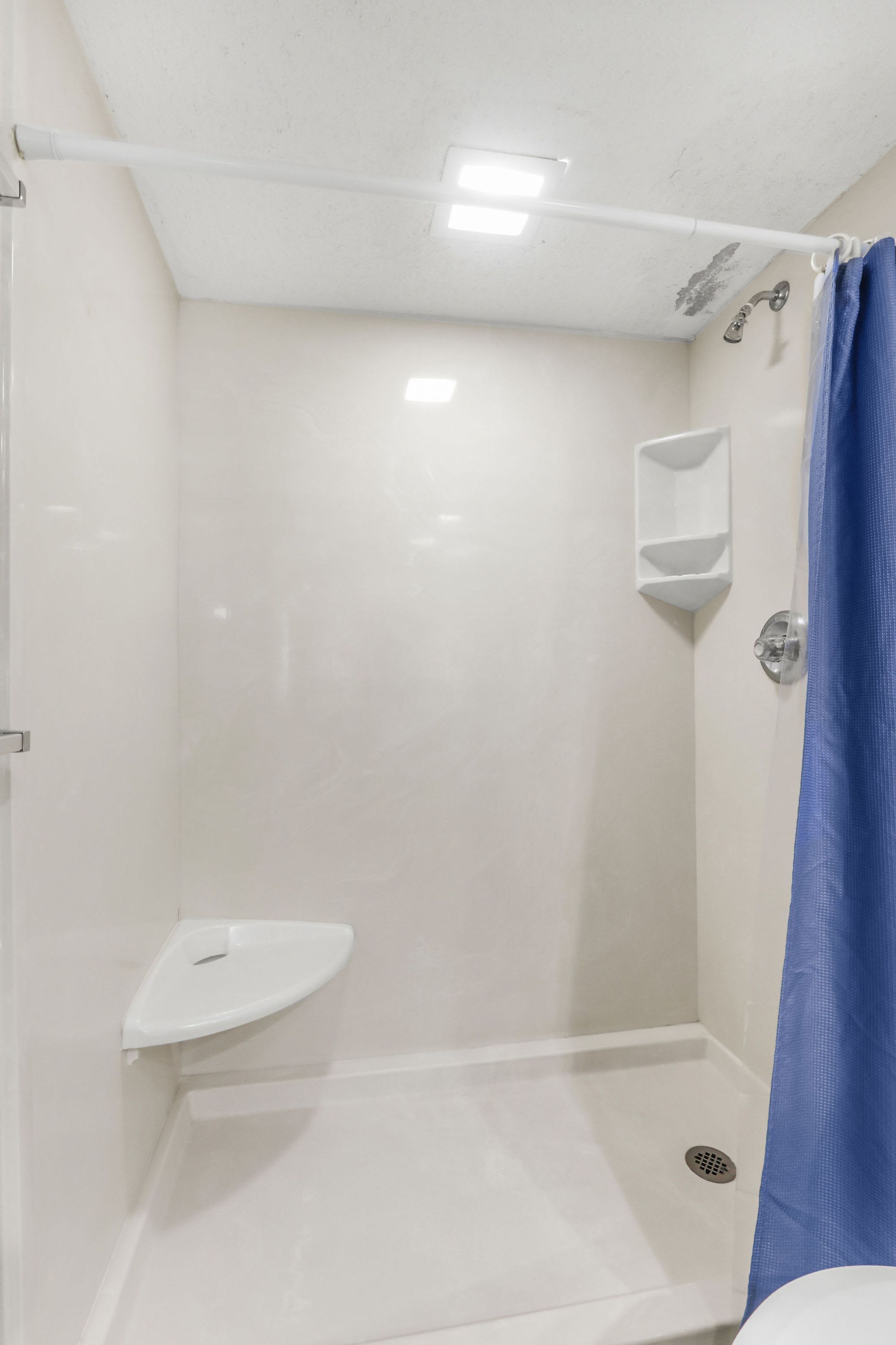 A small, enclosed shower area with a white sink and a showerhead.