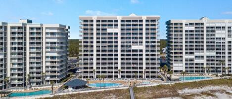 A high-rise hotel with multiple balconies, a pool area, and a beach view.