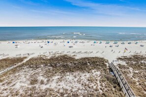 A beach with rows of beach chairs and umbrellas, a sandy path, and a view of the ocean. - Emerald Key 603 Beachfront Balcony 6th Floor Corner Unit (Orange Beach)