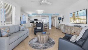 A spacious living area with a sofa, a coffee table, and a TV. - Emerald Key 603 Beachfront Balcony 6th Floor Corner Unit (Orange Beach)