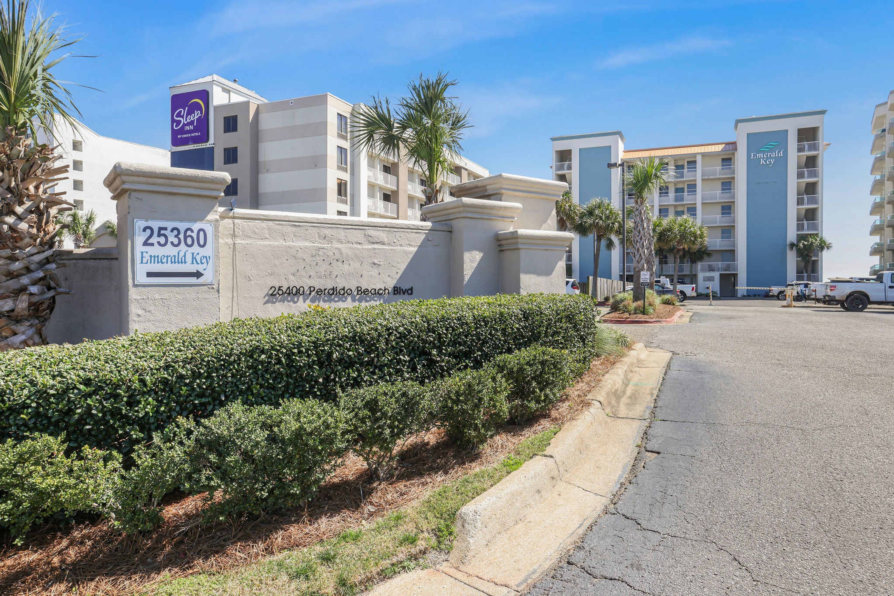A hotel entrance with a sign indicating the address and name 'Emerald Key' at 25360 Perdido Beach Blvd.